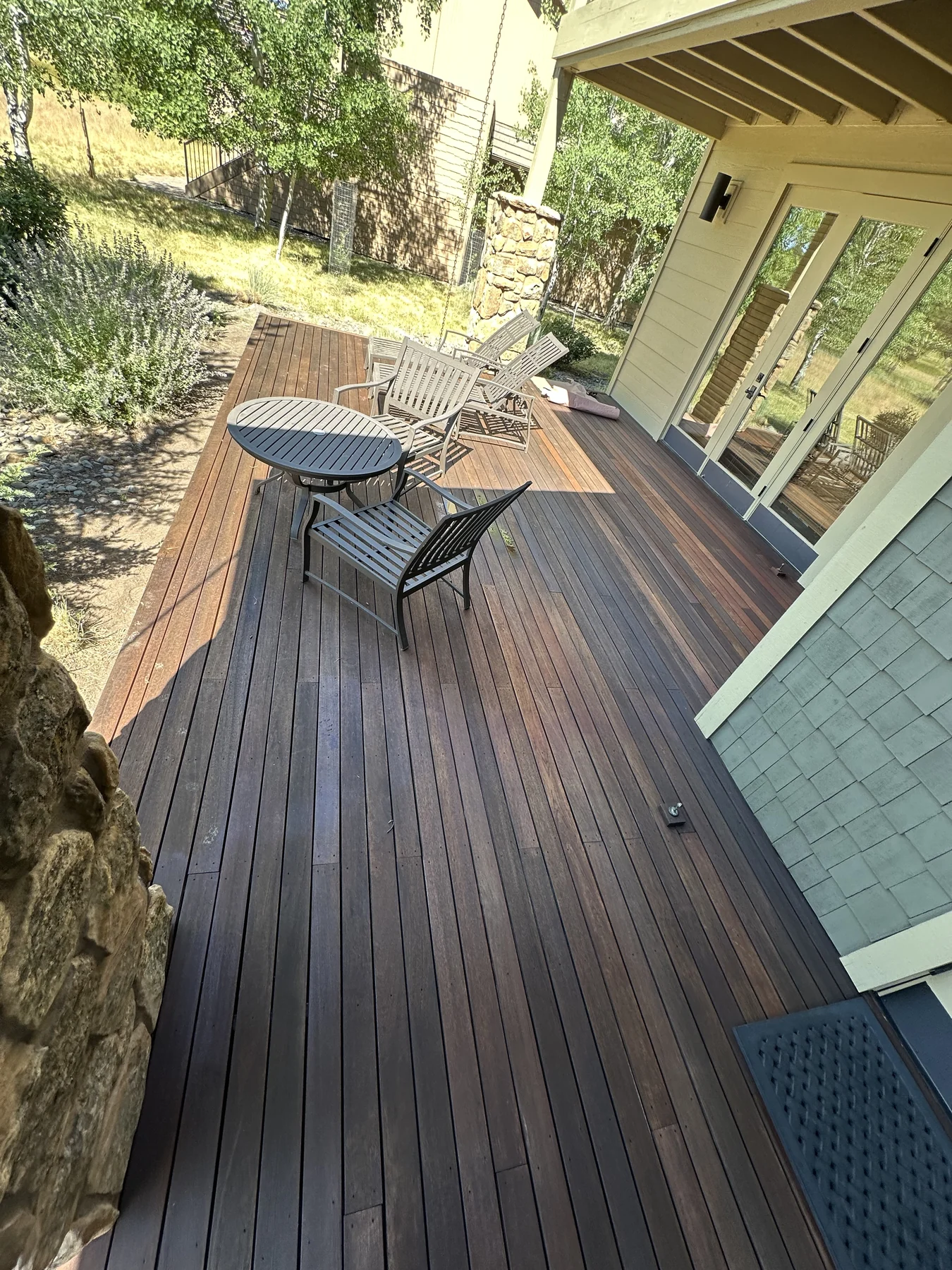 Timber deck with chairs and a round table overlooking trees