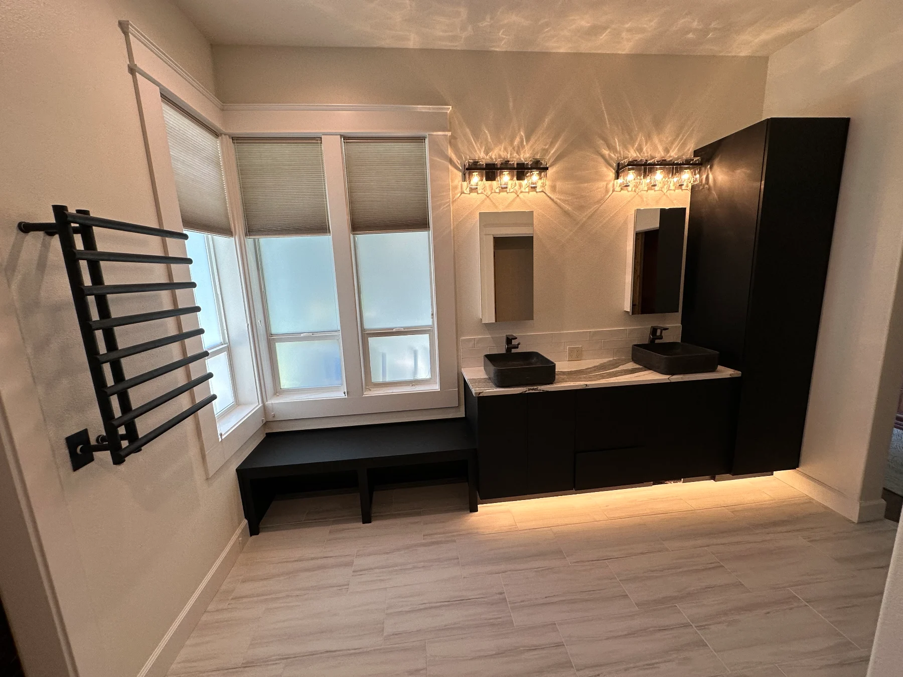 Black double vanity with vessel sinks beside a built-in window seat