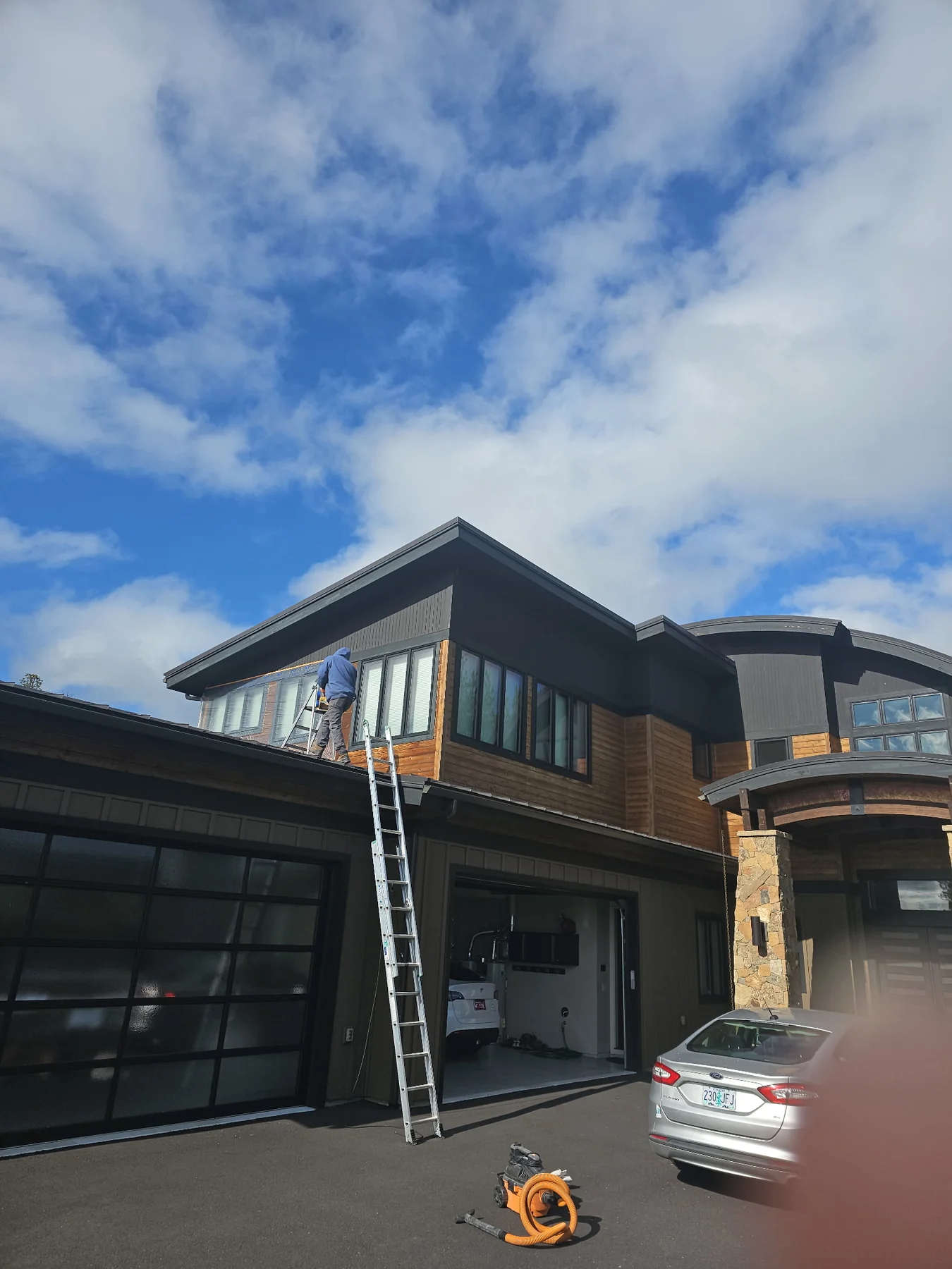 Painter working from a ladder on the upper exterior of a home