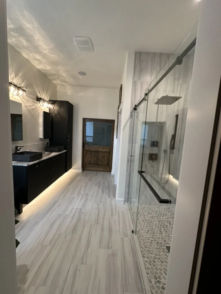 Glass shower, black floating vanity and large-format tile in a finished bathroom