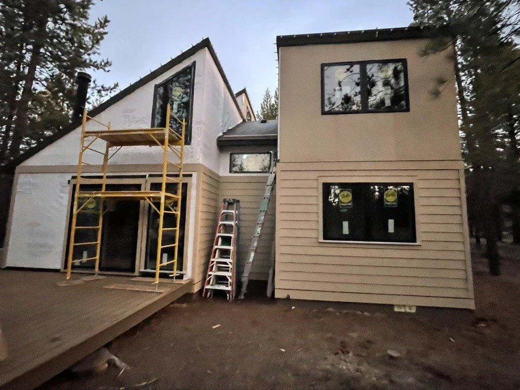 Home exterior with scaffolding, large windows and siding in progress