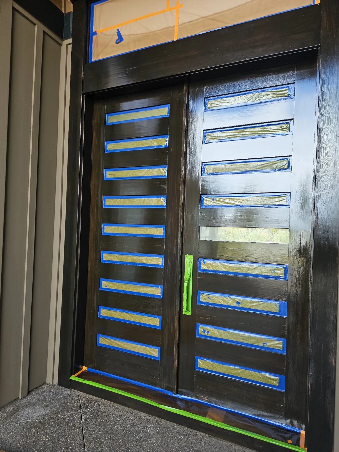 Dark double entry doors with glass panels masked for painting
