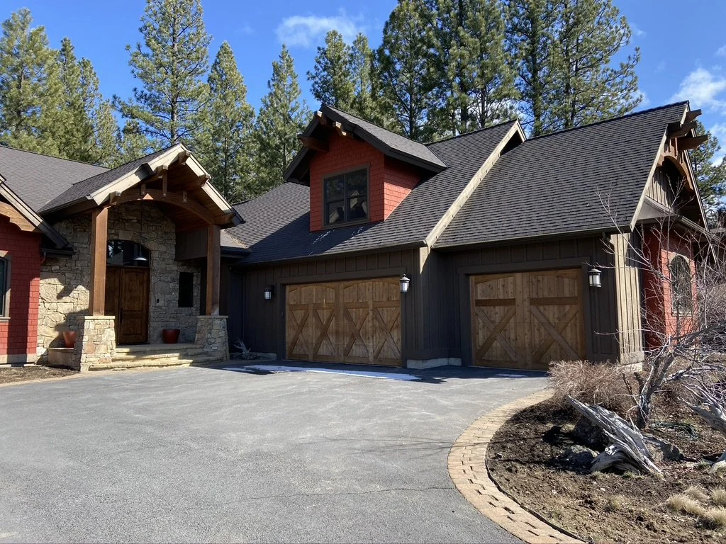 Timber and stone home exterior with warm siding and tall pine trees