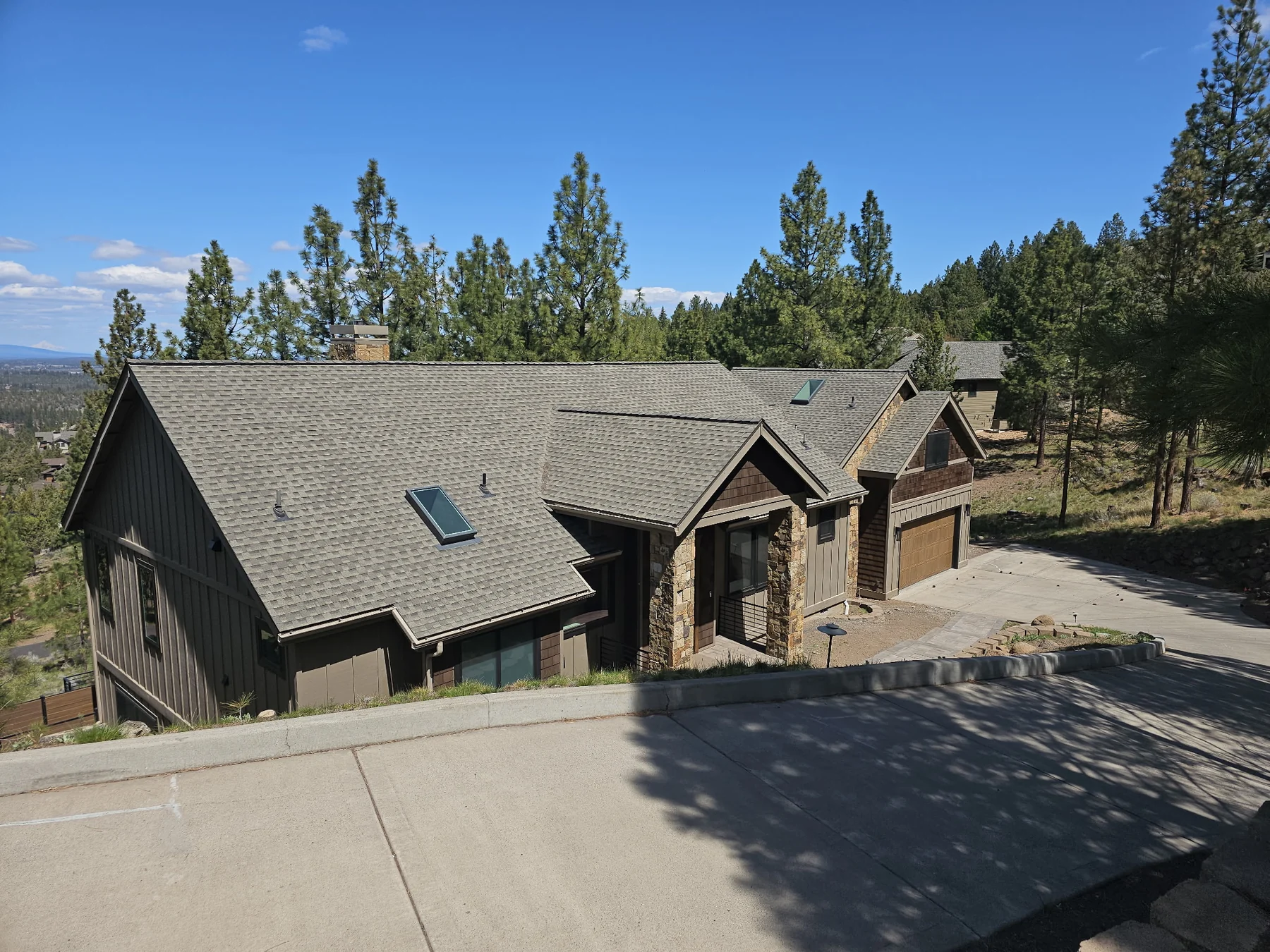 Dark home exterior with timber and stone accents among pine trees