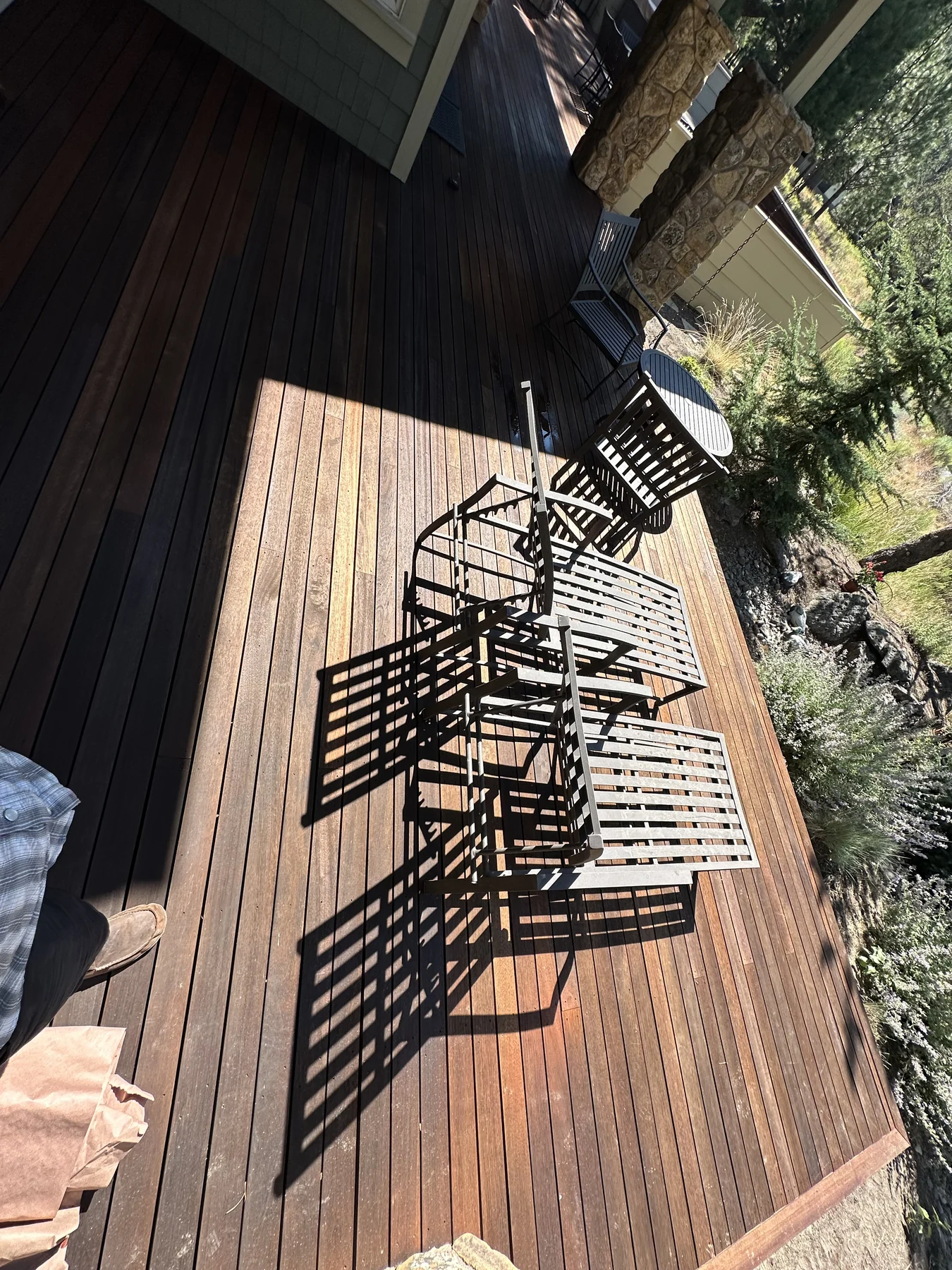 Sunlight and chair shadows on a timber deck beside a covered porch