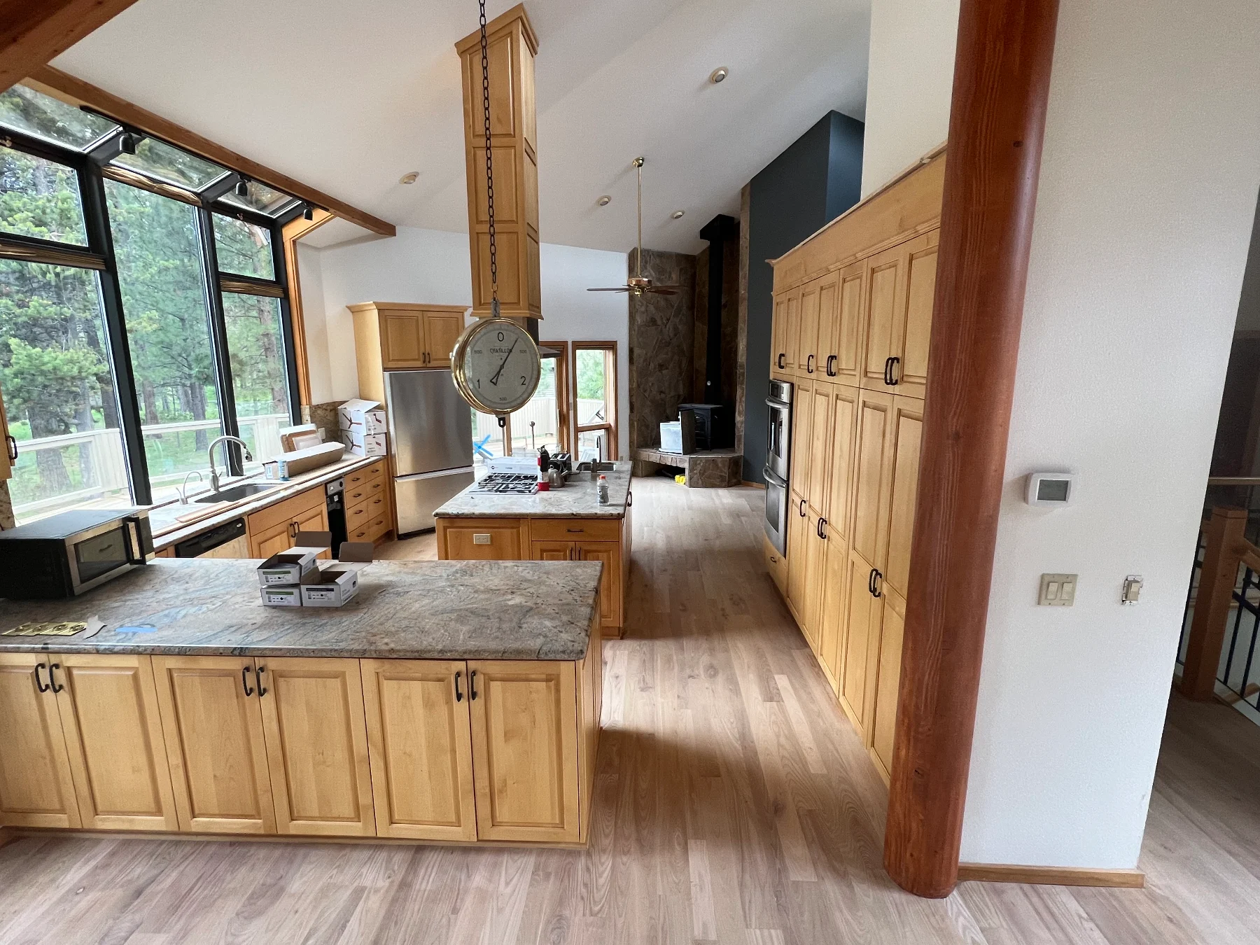 Vaulted kitchen with wood cabinets, tall windows and an adjoining living space